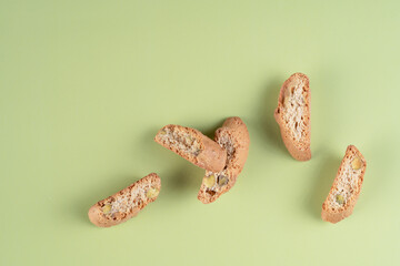 Crunchy Italian biscotti with pistachio nuts, scattered on a soft green surface, ready for a delicious snack