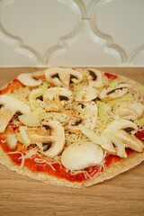 Homemade mushroom and onion pizza on a wooden surface, ready to bake