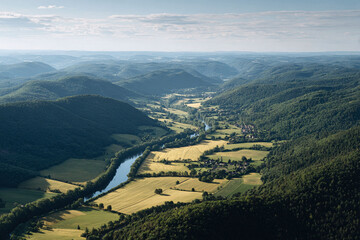 Fototapeta premium Breathtaking aerial view of a river winding through lush green valleys and hills, offering a sense of peace and tranquility. Ideal for travel, nature, or serenity concepts.