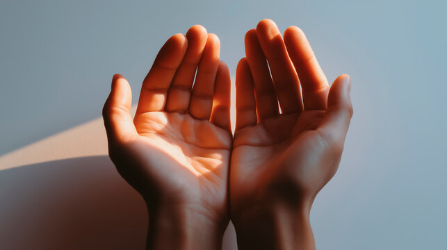 A person's hands outstretched, palms facing out, with a ray of light illuminating them; a concept of hope and faith