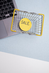Miniature metal shopping basket placed on a laptop keyboard with copy space. E-Commerce and online shopping concept