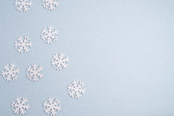 Winter background: clean white snowflakes on a soft pastel blue surface with copy space.
