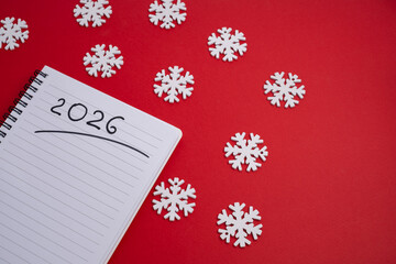 Happy New Year 2026 and a notepad on a colored background. Layout for writing annual business plans, schedules, as well as New Year's resolutions and goals.  
