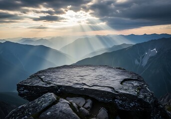 Dramatic sunbeams pierce through stormy clouds illuminating a rugged mountain peak overlooking a vast valley landscape