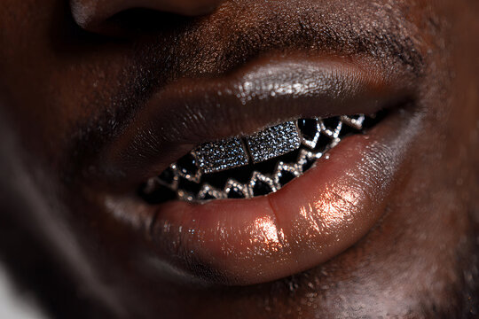 Close-up of a black mans glossy lips with diamond grillz teeth jewelry