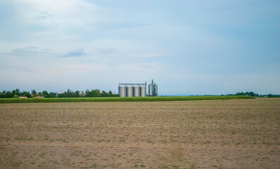 A modern metal grain terminal in a field. A storage tank for agricultural products, an elevator