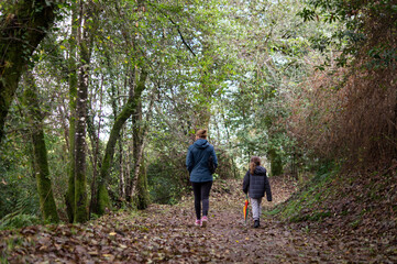 Fototapeta premium Mother and Son Walking on Autumn Forest Trail