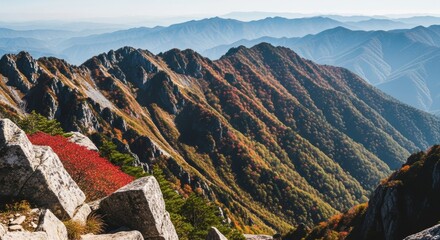 Scenic mountain landscape in peak autumn season. Colorful foliage on a rocky alpine ridge. Outdoor adventure and trekking concept. Breathtaking panoramic view of layered mountain silhouettes