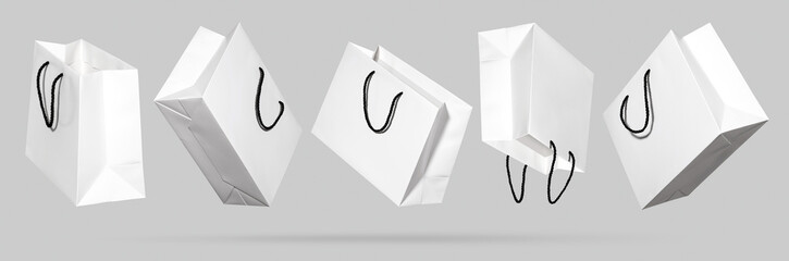 Set of empty, blank white luxury shopping bags with black rope handles floating in air on light gray background. Concept of mockup design for holiday sale banner and discount advertising. Copy space
