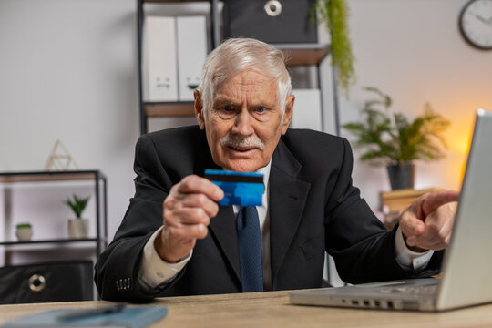 Caucasian angry mad stressed senior businessman try to pay online shopping with smartphone blocked credit card. Annoyed grandpa buying, bank refuse problem unsuccessful payment lack of money balance.