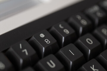 Close-up of vintage computer keyboard keys with sharp focus on symbols and numerals, ideal for tech history projects, retro computing themes, or IT communication materials.