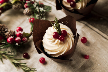 Cupcake with white frosting decoraged with cranberries, festive christmas background