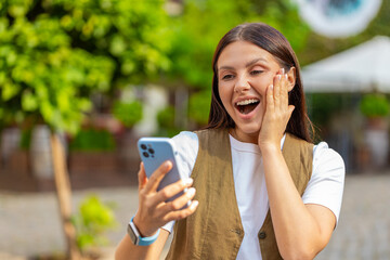 Caucasian young woman using mobile smartphone celebrating win good message news, lottery jackpot...