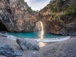 Arcomagno beach in Calabria Italy showing turquoise sea meeting rugged cliffs and hidden caves in backlight symbolizing untouched natural beauty