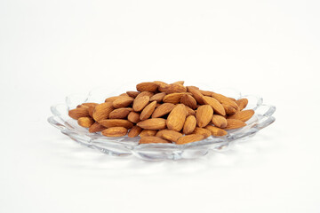 Pile of Raw Almonds in a Decorative Glass Dish on a White Background