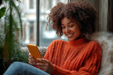 Woman smiling using phone by window with plants