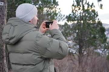A man takes a beautiful landscape photo with his phone camera.