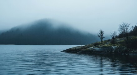 Overcast morning at a tranquil lake. Foggy mountain forest scenery. Natural environment for wellness and travel concepts. Calm water surface with ripples