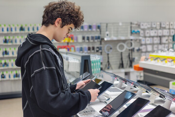 Teenager Choosing a Tablet in Electronics Store – Young Customer Testing Digital Devices, Tech Shopping and Consumer Behavior. gadget choice, digital lifestyle, retail shopping experience. Gen Z