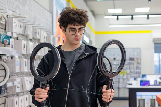 Teenager Choosing Ring Light for Content Creation – Young Blogger Selecting Lighting Equipment in Electronics Store. video recording, streaming, social media content, and vlogging. influencer, Gen Z