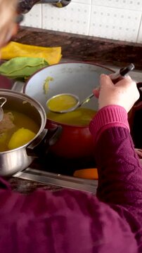 Grandmother cook, pours the broth over the chickpeas through a strainer, cooking at home.