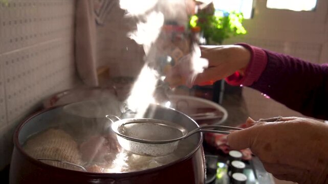 Slow motion. The cook pouring broth into the stew through a strainer.