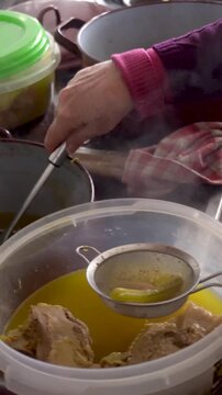  Closeup. The cook pours the broth over the stew through a strainer.