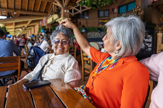 Colombian mother and daughter sharing joyful moment in festive restaurant with Wayuu accessories in Guarne, Antioquia