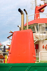 orange chimney with two exhaust pipes on the deck of a boat