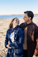 Loving couple walks on beach along sea on sunny autumn day. Weekend and lifestyle concept. Vertical photo. High quality photo