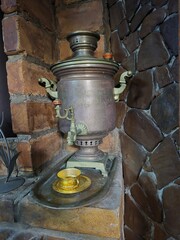 An ancient bronze samovar in a brick kitchen.