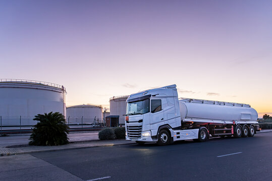 Fuel tanker truck next to large storage tanks