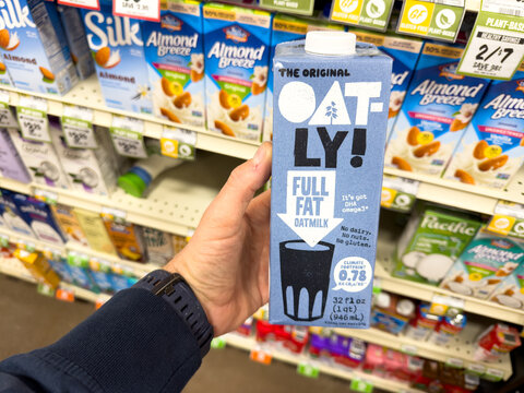 Oatly Full Fat Oatmilk Carton Held in Grocery Store Aisle