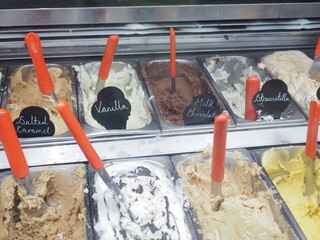 Selection of gelato in shop with flavour labels and scoops