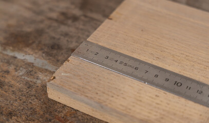 Gros plan sur une règle de menuisier en métal posée sur une planche de bois.