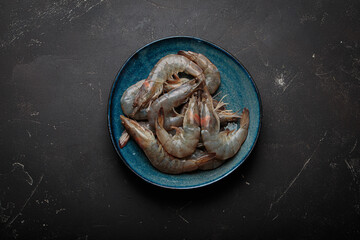 Raw shrimps a delicious composition on a plate textured dark background, preparing for cooking
