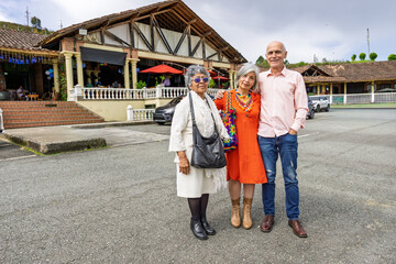 Colombian couple posing with elderly mother in front of rustic restaurant in Guarne, Antioquia.