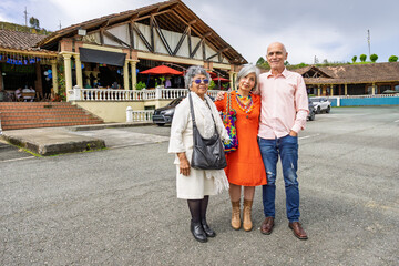 Colombian couple posing with elderly mother in front of rustic restaurant in mountain setting near Guarne, Antioquia.