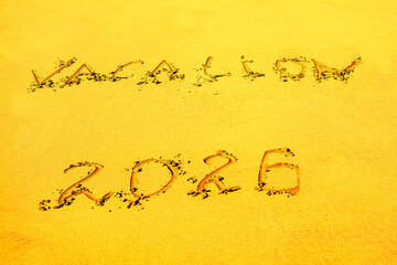 Word VACATION is inscribed into sand with year 