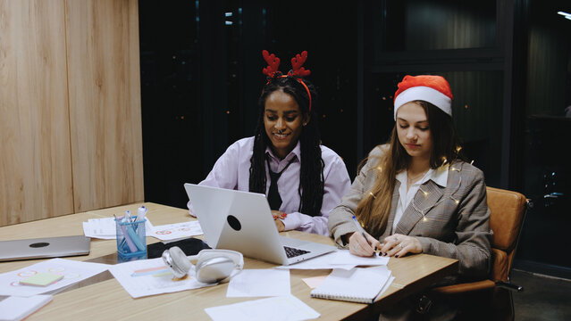 Business woman preparing for Christmas holidays while working late in the office with a laptop and holiday attire