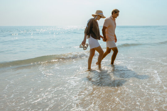 Young caucasian couple enjoying a beach walk by the ocean