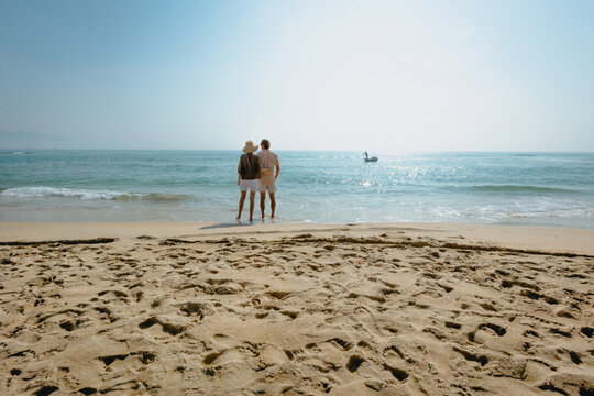 Elderly couple relaxing on sandy beach with ocean view - Powered by Adobe