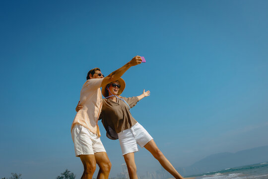 Joyful caucasian couple enjoying beach selfie on sunny day