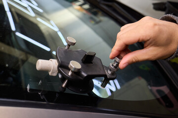 Closeup of technician repairing windshield inside garage, Professional technician employs specialized equipment to mend damaged windshield efficiently and safely
