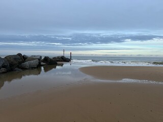 Beautiful natural landscape of sandy beach with vast ocean calm seas and rocky groyne barrier out to horizon in Sea Palling norfolk East Anglia UK on tranquil Winter day cold weather on holiday