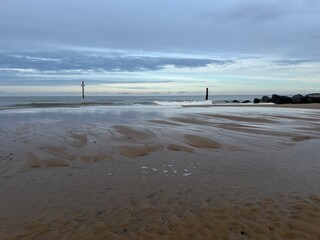 Beautiful natural landscape of sandy beach with vast ocean calm seas and rocky groyne barrier out to horizon in Sea Palling norfolk East Anglia UK on tranquil Winter day cold weather on holiday