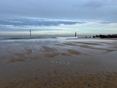 Beautiful natural landscape of sandy beach with vast ocean calm seas and rocky groyne barrier out to horizon in Sea Palling norfolk East Anglia UK on tranquil Winter day cold weather on holiday