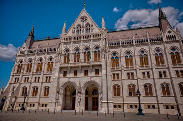 Obraz premium Budapest, Hungary - July 27, 2025: The Hungarian Parliament Building viewed from its garden side, showcasing its magnificent Neo-Gothic architecture with detailed spires and ornate stonework.