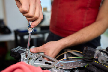Focused technician conducts precise motor repairs, Dedicated technician methodically finetunes small motor assembly with specialized tools in workshop environment