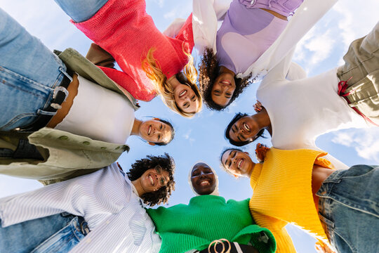 Happy group of diverse young women forming circle outdoors. Multiracial female friends smiling and showing unity and support. Community and empowerment concept.